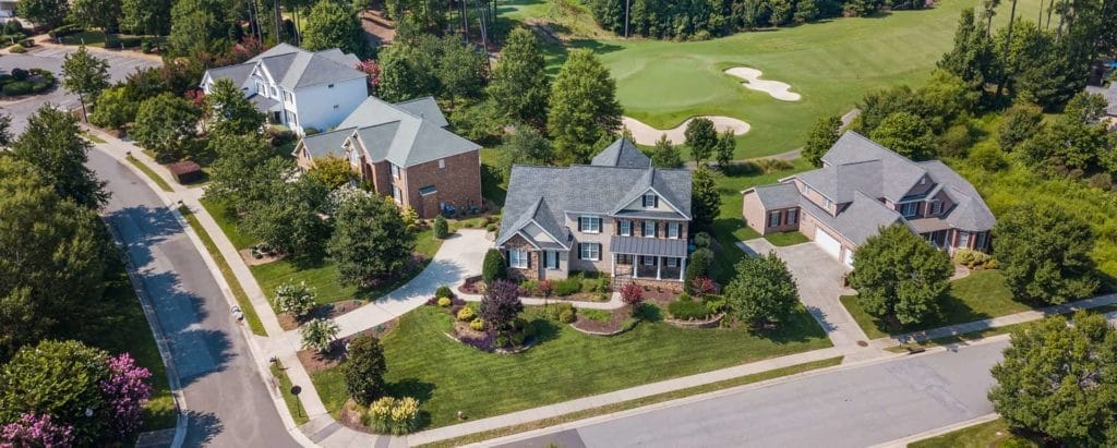 An aerial view of a home with a golf course in the background.