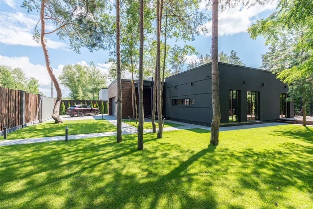 A modern house surrounded by trees and grass.